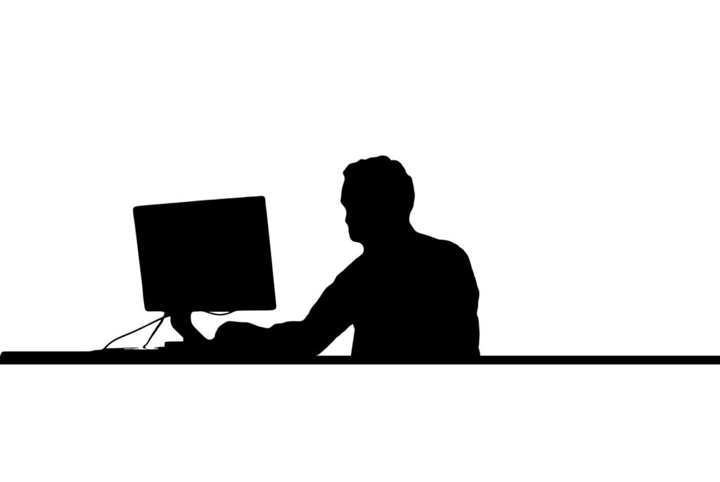 man silhouetted sitting at a desk